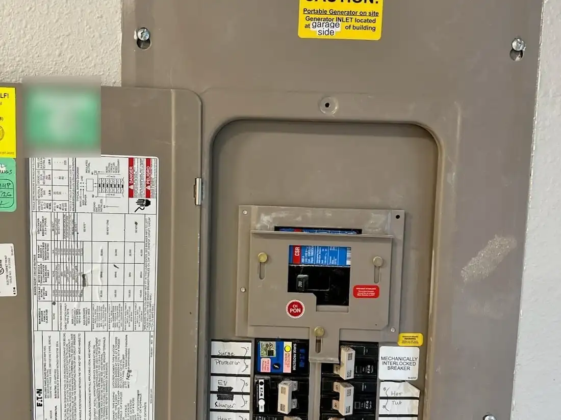 Main electrical panel in a new home with hand-labeled circuits for an EV charger and a heat pump, a whole-home surge protector and a mechanical generator interlock